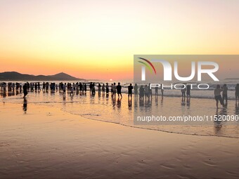 Tourists watch the sunrise at the Golden Beach in Qingdao, China, on August 28, 2024. (