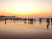 Tourists watch the sunrise at the Golden Beach in Qingdao, China, on August 28, 2024. (