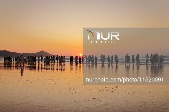 Tourists watch the sunrise at the Golden Beach in Qingdao, China, on August 28, 2024. 