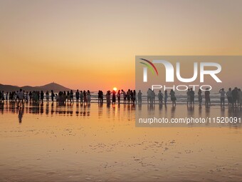 Tourists watch the sunrise at the Golden Beach in Qingdao, China, on August 28, 2024. (