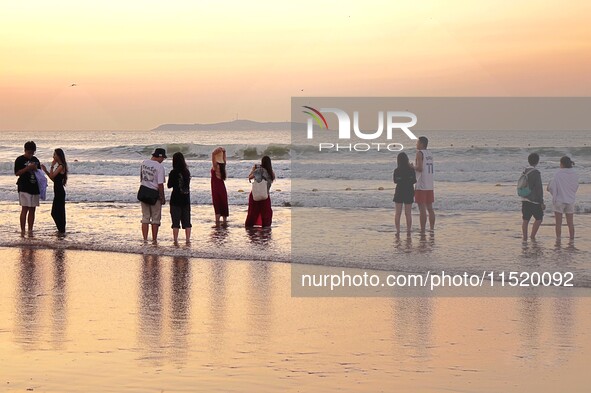 Tourists watch the sunrise at the Golden Beach in Qingdao, China, on August 28, 2024. 