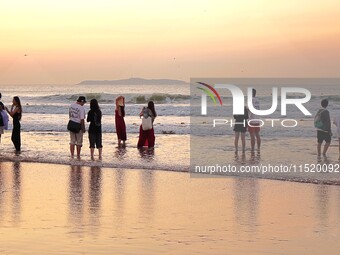 Tourists watch the sunrise at the Golden Beach in Qingdao, China, on August 28, 2024. (