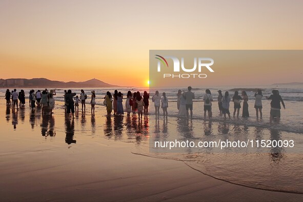 Tourists watch the sunrise at the Golden Beach in Qingdao, China, on August 28, 2024. 