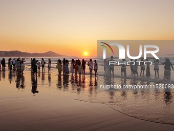 Tourists watch the sunrise at the Golden Beach in Qingdao, China, on August 28, 2024. (