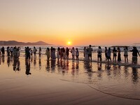 Tourists watch the sunrise at the Golden Beach in Qingdao, China, on August 28, 2024. (