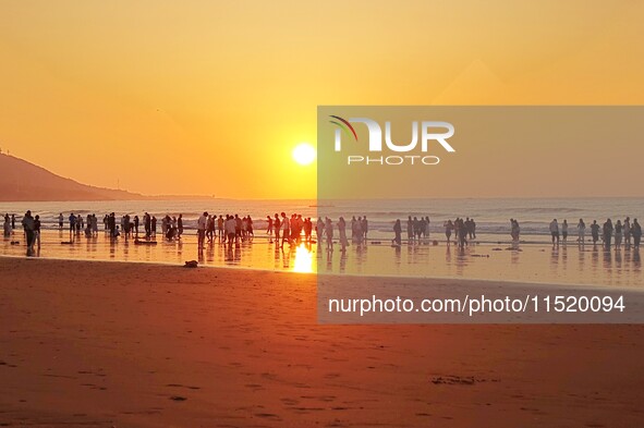 Tourists watch the sunrise at the Golden Beach in Qingdao, China, on August 28, 2024. 