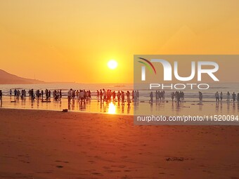 Tourists watch the sunrise at the Golden Beach in Qingdao, China, on August 28, 2024. (