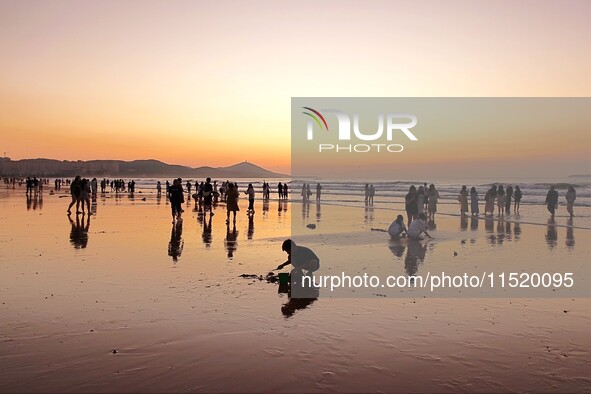 Tourists watch the sunrise at the Golden Beach in Qingdao, China, on August 28, 2024. 