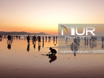 Tourists watch the sunrise at the Golden Beach in Qingdao, China, on August 28, 2024. (