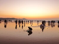 Tourists watch the sunrise at the Golden Beach in Qingdao, China, on August 28, 2024. (