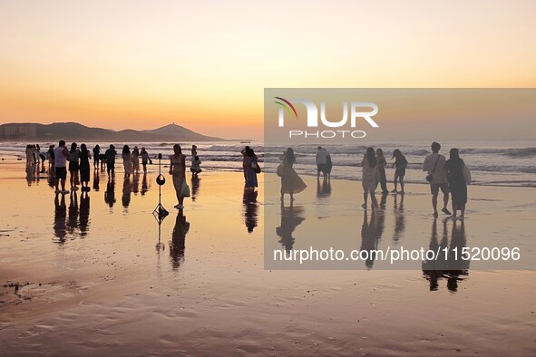 Tourists watch the sunrise at the Golden Beach in Qingdao, China, on August 28, 2024. 