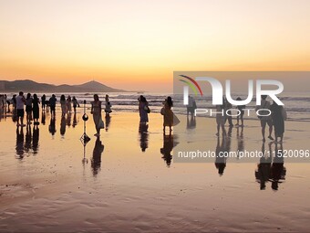 Tourists watch the sunrise at the Golden Beach in Qingdao, China, on August 28, 2024. (