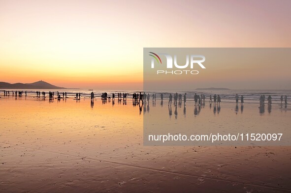 Tourists watch the sunrise at the Golden Beach in Qingdao, China, on August 28, 2024. 