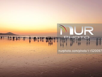 Tourists watch the sunrise at the Golden Beach in Qingdao, China, on August 28, 2024. (