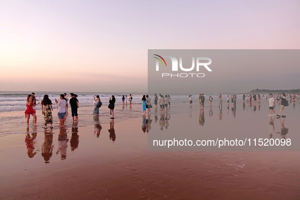 Tourists watch the sunrise at the Golden Beach in Qingdao, China, on August 28, 2024. 