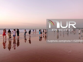 Tourists watch the sunrise at the Golden Beach in Qingdao, China, on August 28, 2024. (