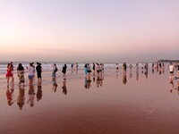 Tourists watch the sunrise at the Golden Beach in Qingdao, China, on August 28, 2024. (