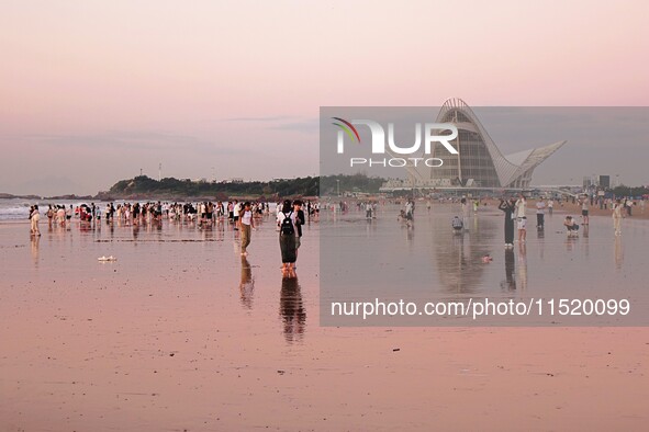 Tourists watch the sunrise at the Golden Beach in Qingdao, China, on August 28, 2024. 