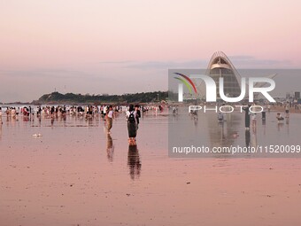 Tourists watch the sunrise at the Golden Beach in Qingdao, China, on August 28, 2024. (