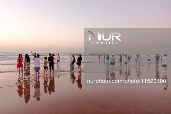 Tourists watch the sunrise at the Golden Beach in Qingdao, China, on August 28, 2024. 