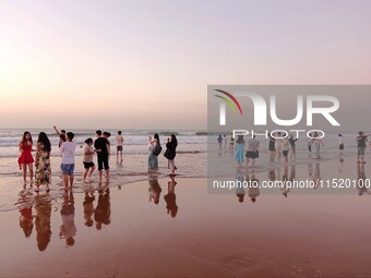 Tourists watch the sunrise at the Golden Beach in Qingdao, China, on August 28, 2024. (