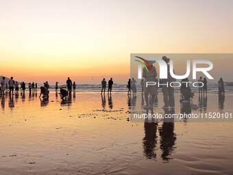 Tourists watch the sunrise at the Golden Beach in Qingdao, China, on August 28, 2024. (