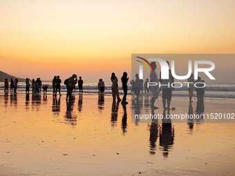 Tourists watch the sunrise at the Golden Beach in Qingdao, China, on August 28, 2024. (