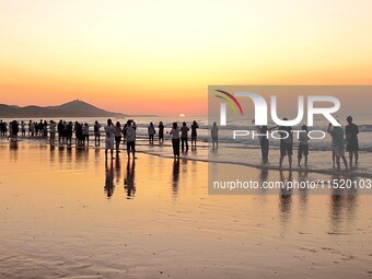 Tourists watch the sunrise at the Golden Beach in Qingdao, China, on August 28, 2024. (