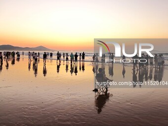 Tourists watch the sunrise at the Golden Beach in Qingdao, China, on August 28, 2024. (