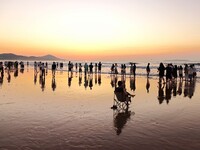 Tourists watch the sunrise at the Golden Beach in Qingdao, China, on August 28, 2024. (