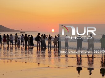 Tourists watch the sunrise at the Golden Beach in Qingdao, China, on August 28, 2024. (