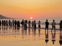 Tourists watch the sunrise at the Golden Beach in Qingdao, China, on August 28, 2024. (