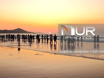 Tourists watch the sunrise at the Golden Beach in Qingdao, China, on August 28, 2024. (