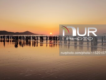 Tourists watch the sunrise at the Golden Beach in Qingdao, China, on August 28, 2024. (