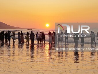 Tourists watch the sunrise at the Golden Beach in Qingdao, China, on August 28, 2024. (