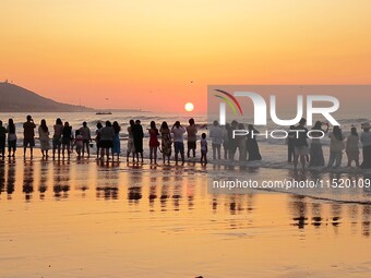 Tourists watch the sunrise at the Golden Beach in Qingdao, China, on August 28, 2024. (