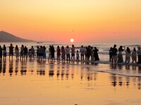 Tourists watch the sunrise at the Golden Beach in Qingdao, China, on August 28, 2024. (