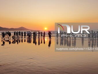 Tourists watch the sunrise at the Golden Beach in Qingdao, China, on August 28, 2024. (