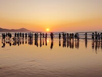 Tourists watch the sunrise at the Golden Beach in Qingdao, China, on August 28, 2024. (