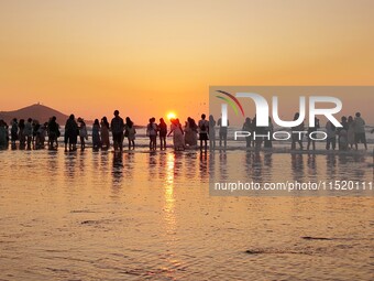 Tourists watch the sunrise at the Golden Beach in Qingdao, China, on August 28, 2024. (