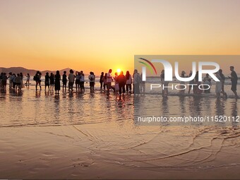 Tourists watch the sunrise at the Golden Beach in Qingdao, China, on August 28, 2024. (