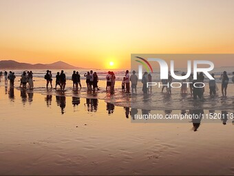 Tourists watch the sunrise at the Golden Beach in Qingdao, China, on August 28, 2024. (