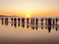 Tourists watch the sunrise at the Golden Beach in Qingdao, China, on August 28, 2024. (