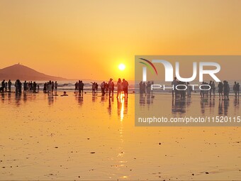 Tourists watch the sunrise at the Golden Beach in Qingdao, China, on August 28, 2024. (