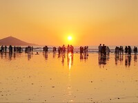 Tourists watch the sunrise at the Golden Beach in Qingdao, China, on August 28, 2024. (