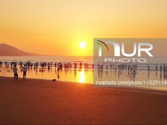 Tourists watch the sunrise at the Golden Beach in Qingdao, China, on August 28, 2024. (