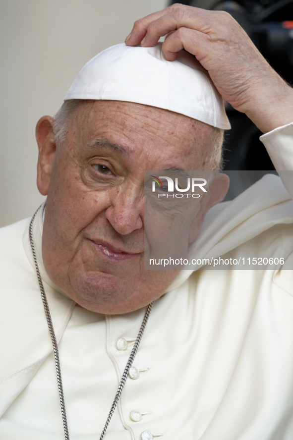 Pope Francis touches his skullcap as he arrives for his weekly general audience in St. Peter's Square at The Vatican, on August 28, 2024. 