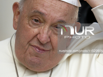 Pope Francis touches his skullcap as he arrives for his weekly general audience in St. Peter's Square at The Vatican, on August 28, 2024. (