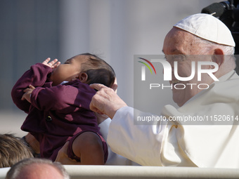 Pope Francis caresses a newborn as he arrives for his weekly General Audience in Saint Peter's Square, Vatican City, on August 28, 2024. (