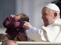 Pope Francis caresses a newborn as he arrives for his weekly General Audience in Saint Peter's Square, Vatican City, on August 28, 2024. (